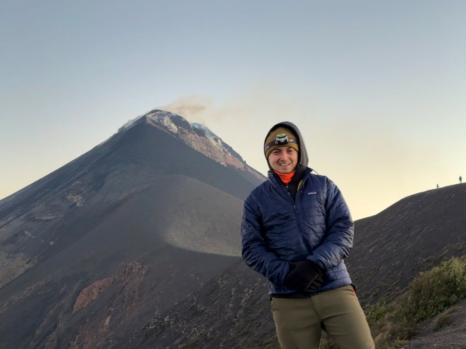 Brady on a volcanic ridge in front of a smoking Volcán de Fuego, Guatemala